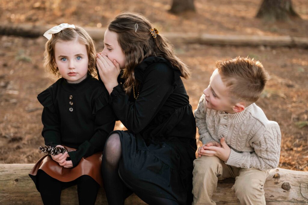 Three children share secrets at photography session in St. Charles, Missouri.