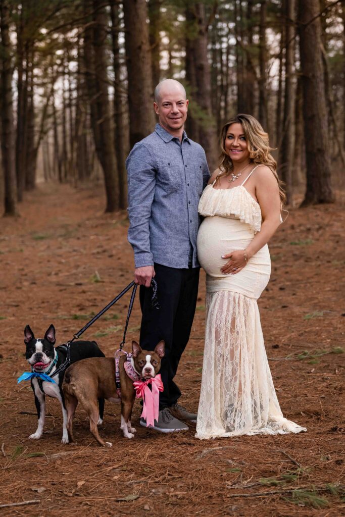 Joyful maternity couple photoshoot at Busch Conservation Area — expecting parents share an intimate moment in the forest with their two dogs, getting excited for their upcoming baby!
