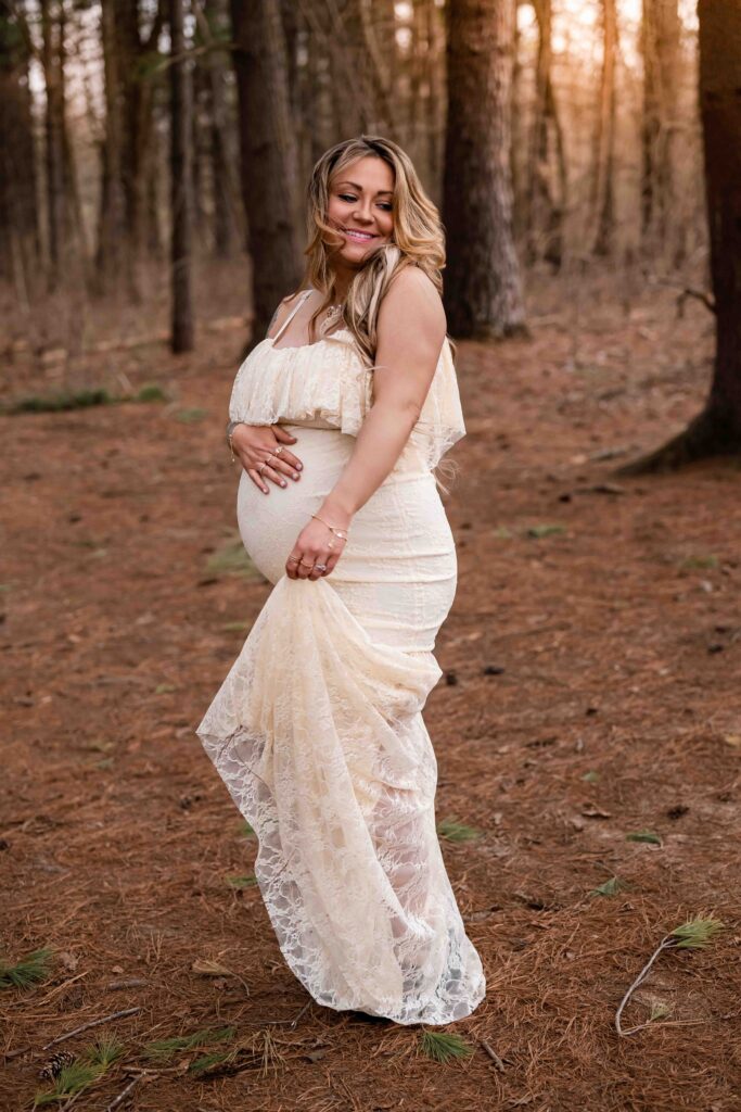 "Stylish outdoor maternity portrait at Busch Conservation Area featuring pregnant woman in lace dress dancing in the sunset and cradling baby bump during golden hour — inspiration for bold and natural pregnancy photography."